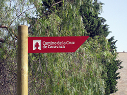 Poste con flecha en medio rural, en la que figura en logo y nombre del Camino Poste con flecha en medio rural, en la que figura en logo y nombre del Camino
